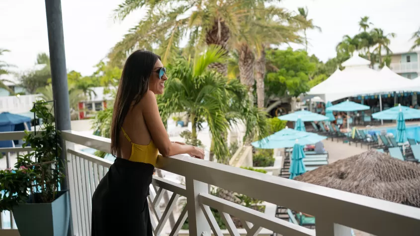 Woman looking out from a balcony at the resort pool